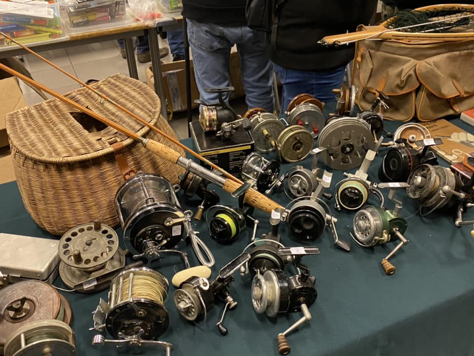Table de la Bourse avec des moulinets anciens, une canne en bambou et un panier de pêche en osier