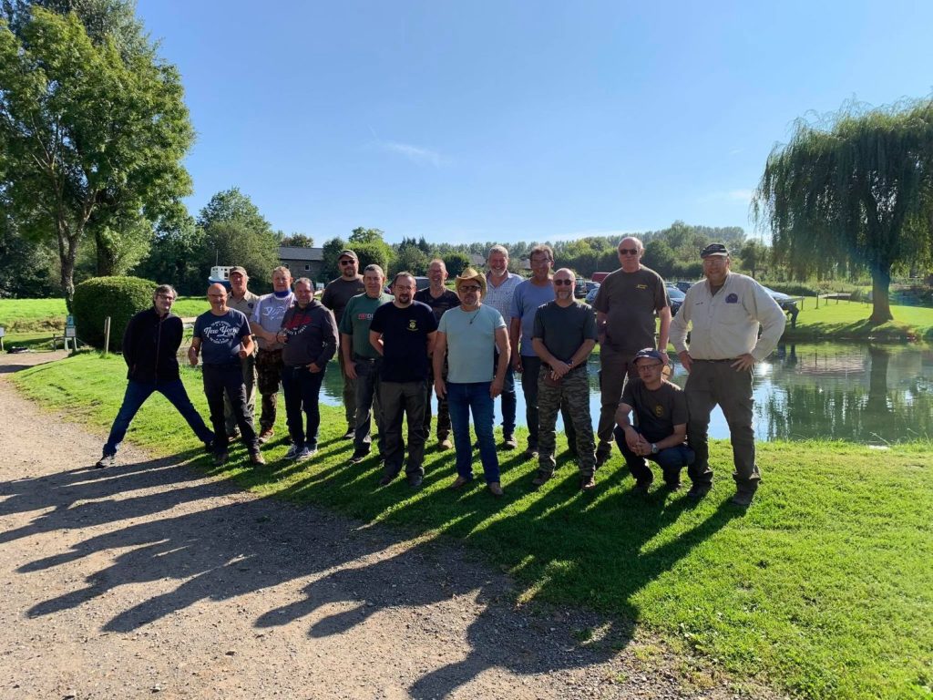 Groupe de membres du club posant au soleil au bord d’un étang, lors d’une sortie