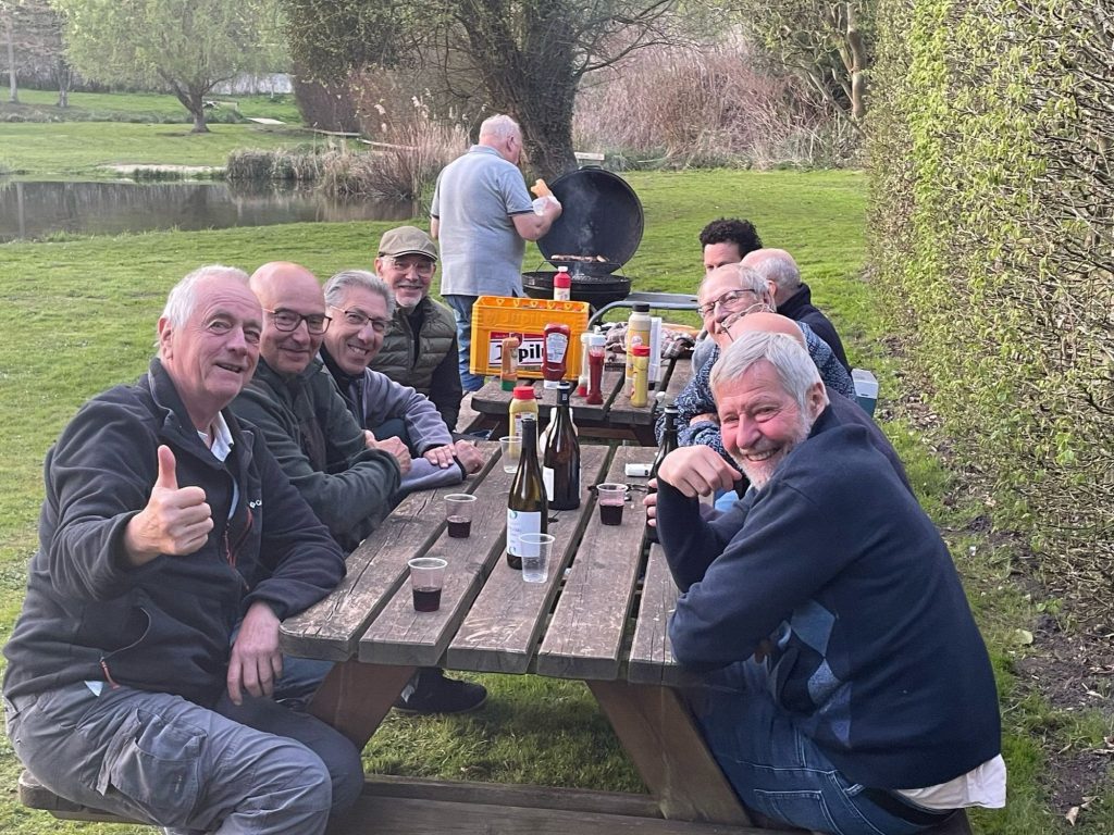Des membres rient autour d’une table de pique-nique, au bord de l’eau